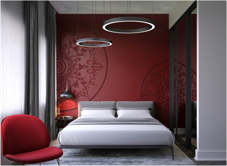Arredamento camera da letto, parete dipinta di rosso con ornamenti, lampadario ad anelli