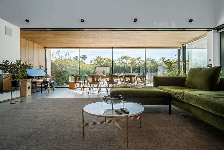 Soluzioni per dividere soggiorno e cucina, tavolino basso rotondo, divano verde in tessuto