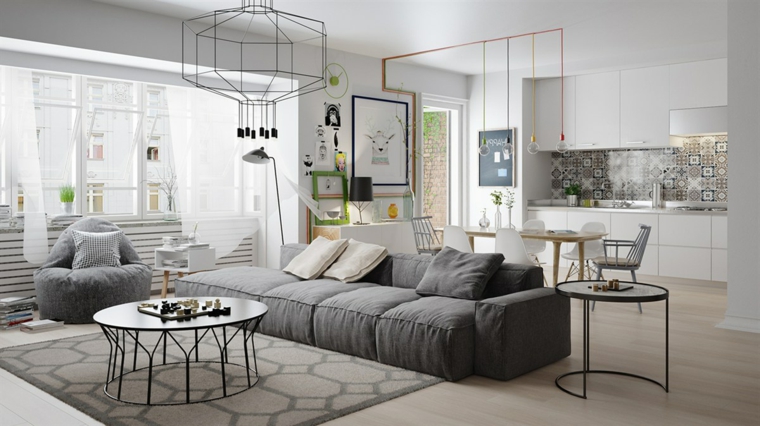 Open space soggiorno cucina, divano di colore grigio, lampade sospese da soffitto