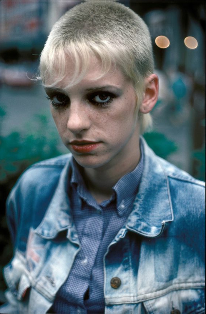 abbigliamento- anni-80-ragazza-skinhead-bionda-giacca-camicia-jeans-matita-nera-occhi