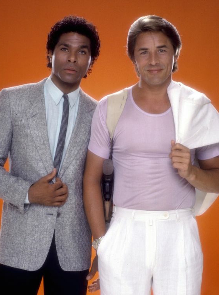 look-anni-80-uomo-protagonisti-Miami Vice-t-shirt-rosa-pastello-pantaloni-giacca-bianchi-giacca-elegante-cravatta-sottile