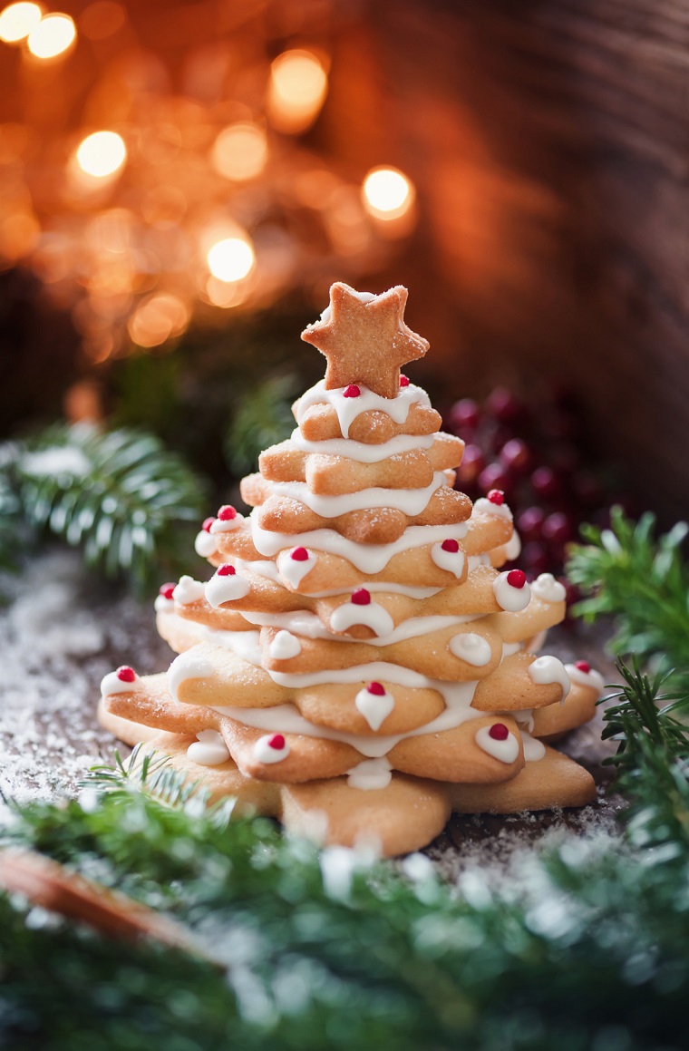 Albero di Natale da biscotti con una forma di stelle decorati con della glassa e bacche 
