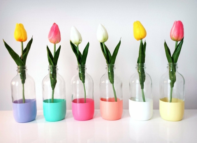 dei vasi realizzate con delle bottiglie, colorati e con all'interno dei fiori: idea regalo fai da te con il riciclo
