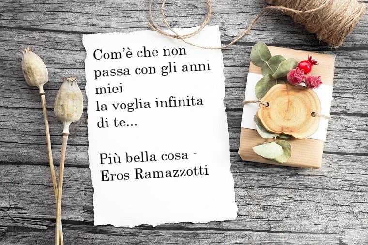 Testo canzone Più bella cosa di Eros Ramazzotti, frase scritta su un foglio bianco con decori in stile rustico 