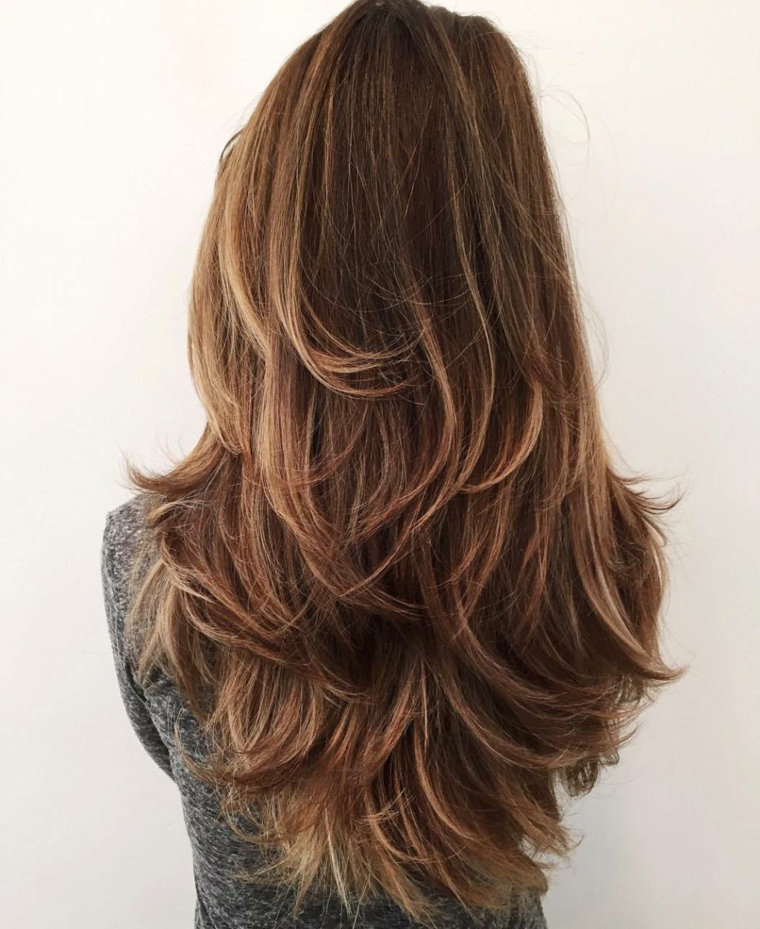 Ragazza con un taglio di capelli castani scalati, volume alle radici 