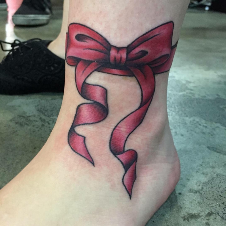 tatuaggio a forma di fiocco rosso realizzato sopra la caviglia