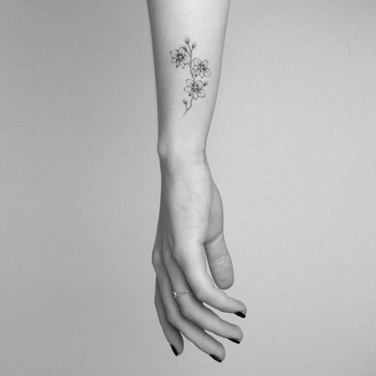 Tatuaggi belli, donna con un piccolo tatto di fiori sul braccio di colore nero con poche sfumature 
