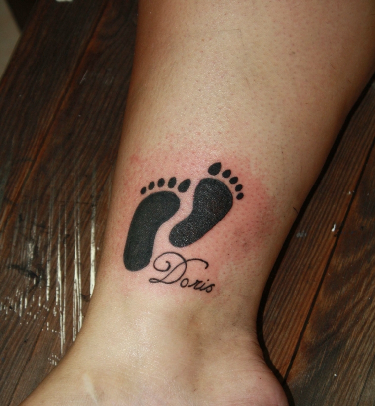 tatuaggio con disegnato i piedini e il nome del proprio figlio sulla caviglia
