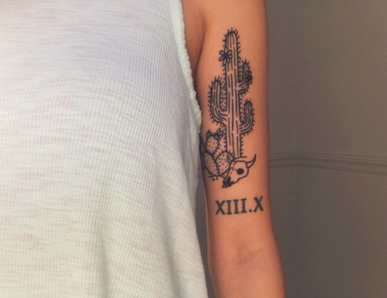 Tatuaggi belli, disegno di un cactus e data con le cifre romane sul braccio di una donna 