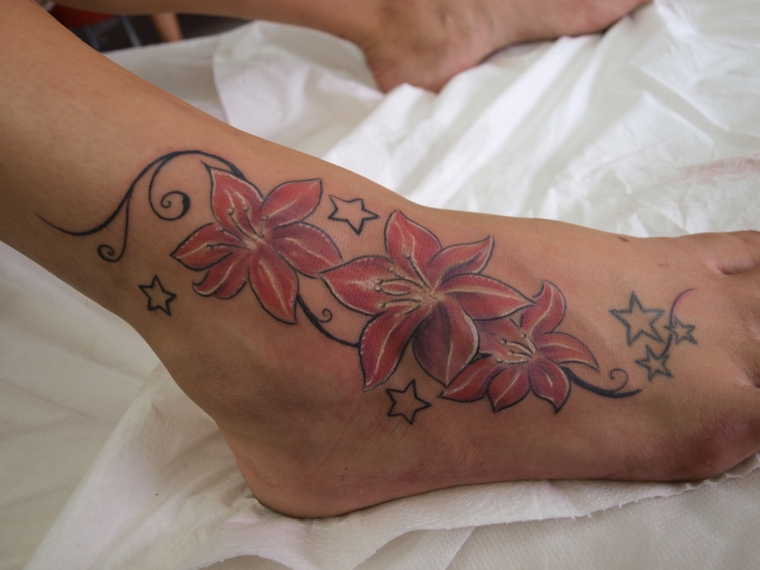 tattoo sulla caviglia, un disegno raffigurante dei fiori con decorazioni e piccole stelle