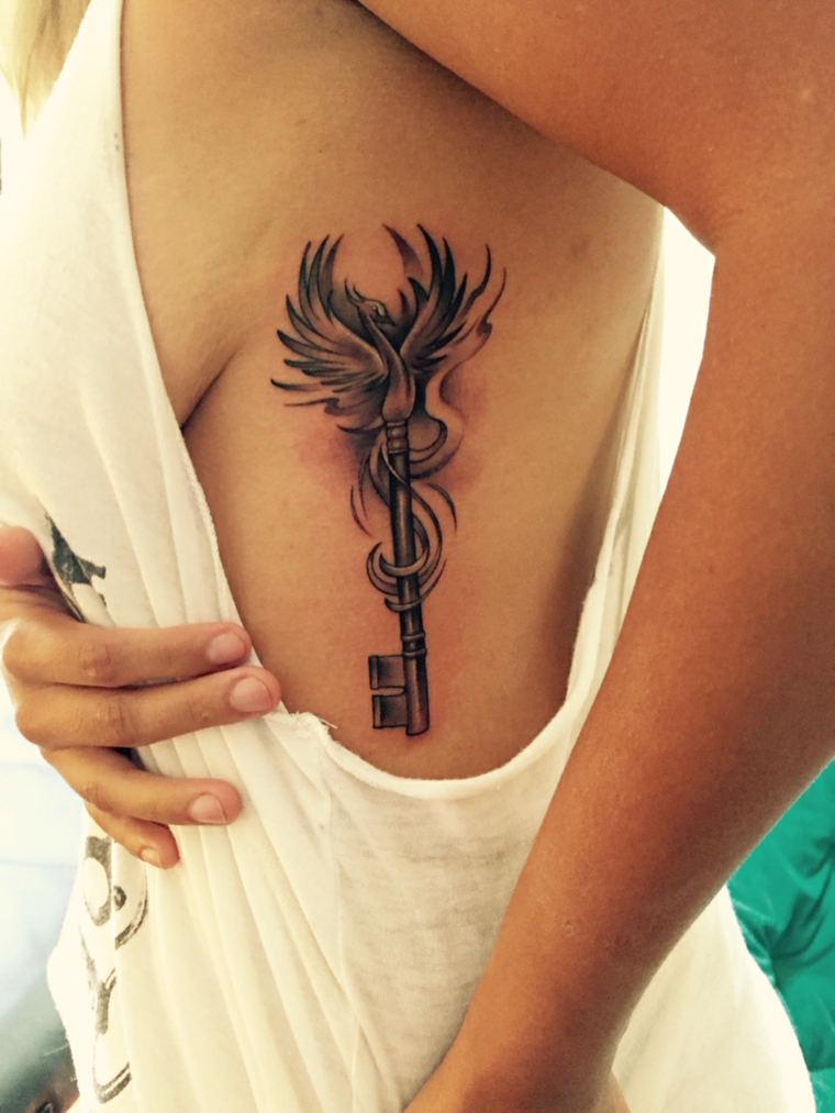 Uccello fenice sul tatuaggio di una donna, idea con una chiave vintage e sfumature colore più chiaro 