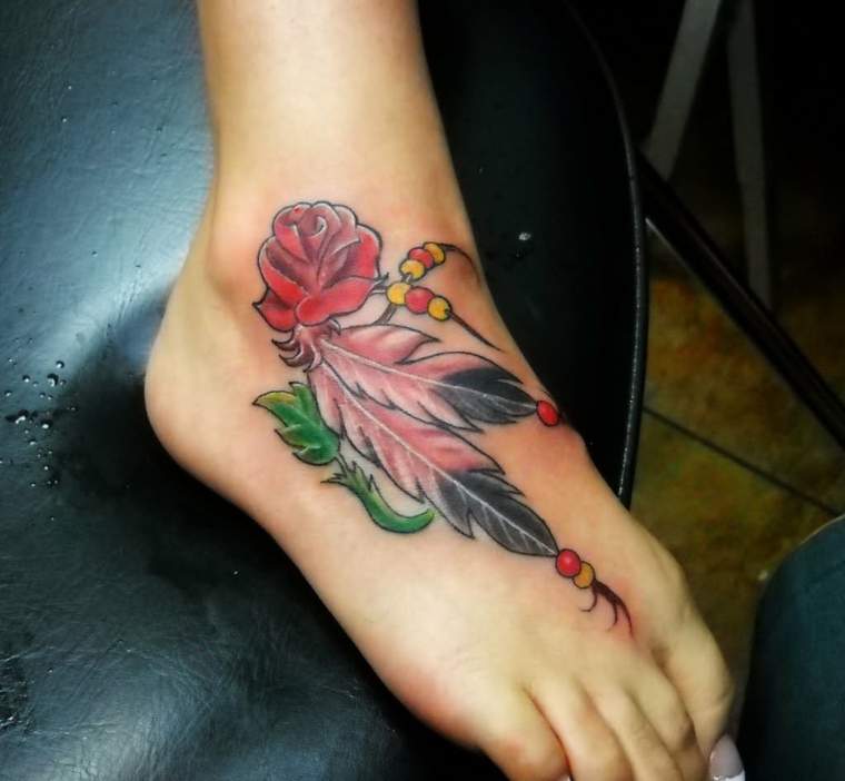 tatuaggio sulla caviglia, che interessa anche il piede con una rosa rossa e delle piume