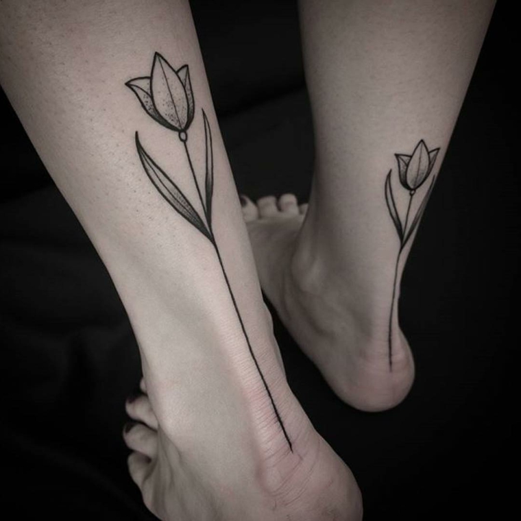 tattoo forma di fiore stilizzato in bianco e nero nella parte posteriore della caviglia