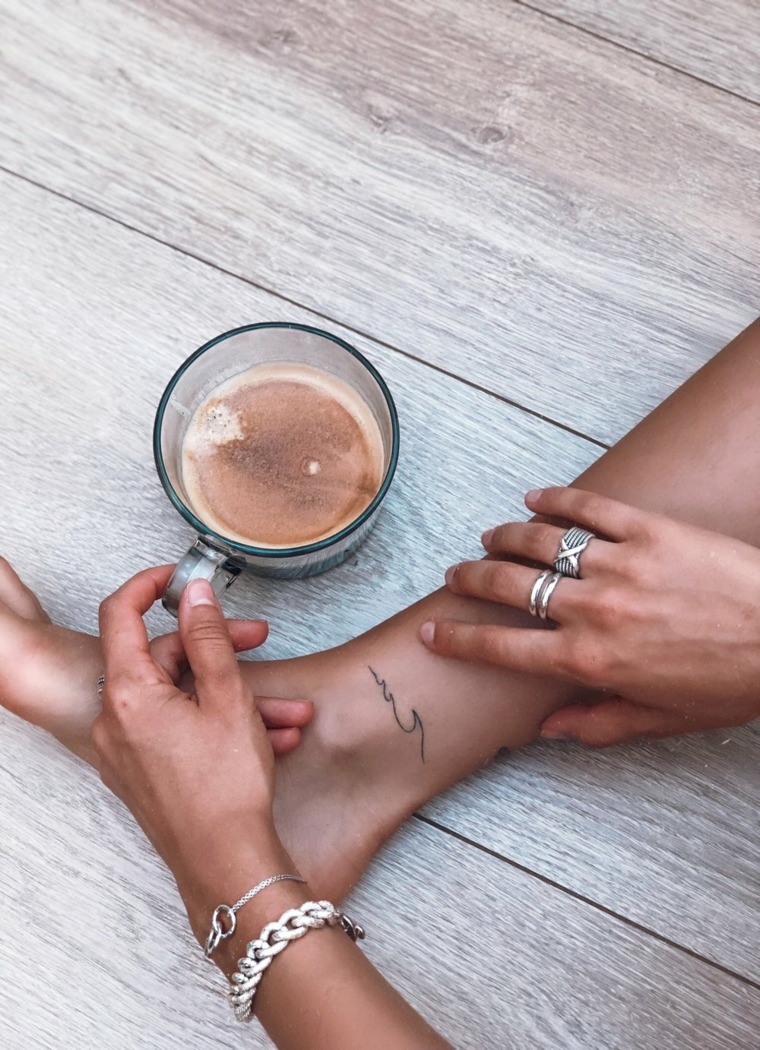 Tatuaggi caviglia, donna con tazza di caffè, disegno tattoo onda di mare sul piede