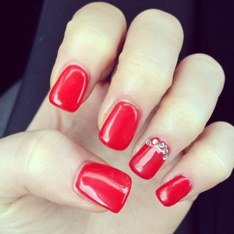 unghie rosse decorate, una manicure a tinta unita con top coat brillante e glitter sull'anulare