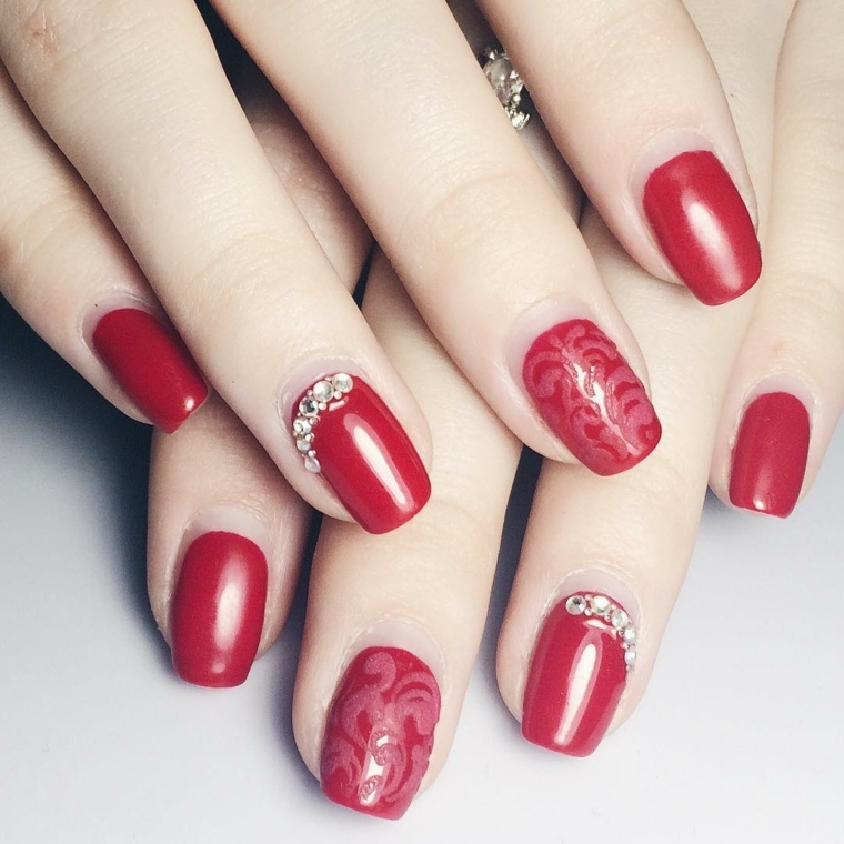nail rosse, una manicure particolare realizzata con dei glitter e alcune decorazioni