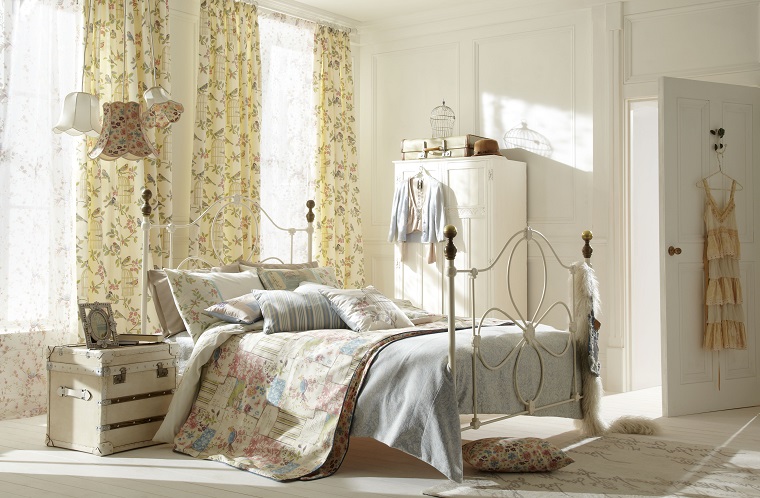 Stile shabby per una camera da letto arredata con mobili in legno e ferro battuto 