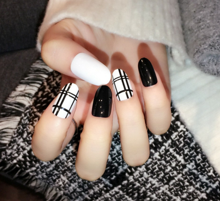 Decorazioni unghie gel con base di colore bianco e nero, linee decorative sull'anulare e il pollice 