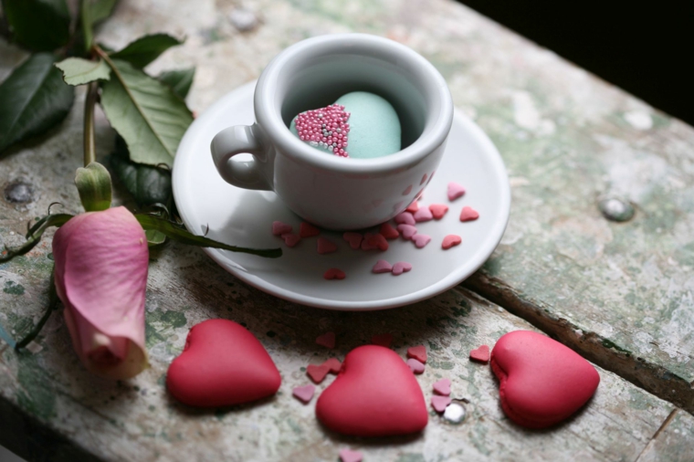 Biscotti macarons di colore rosa a forma di cuore, tazza di caffè con sorpresa dentro 