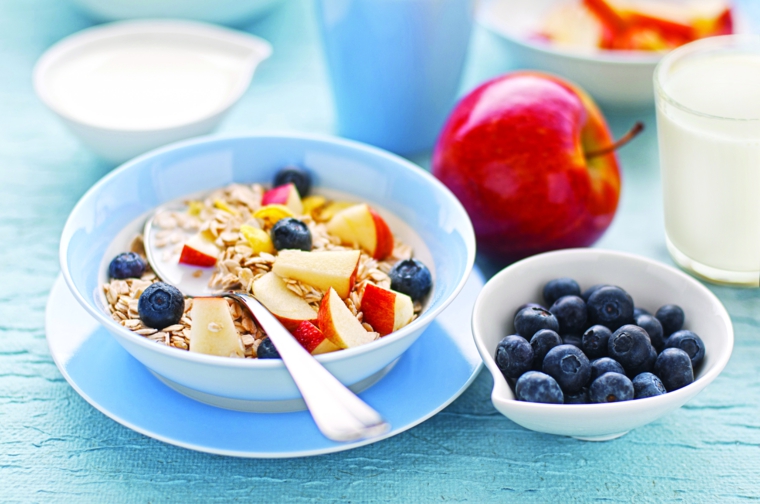 Colazione dietetica con yogurt e cereali, aggiunta di pezzettini di mela e mirtilli 