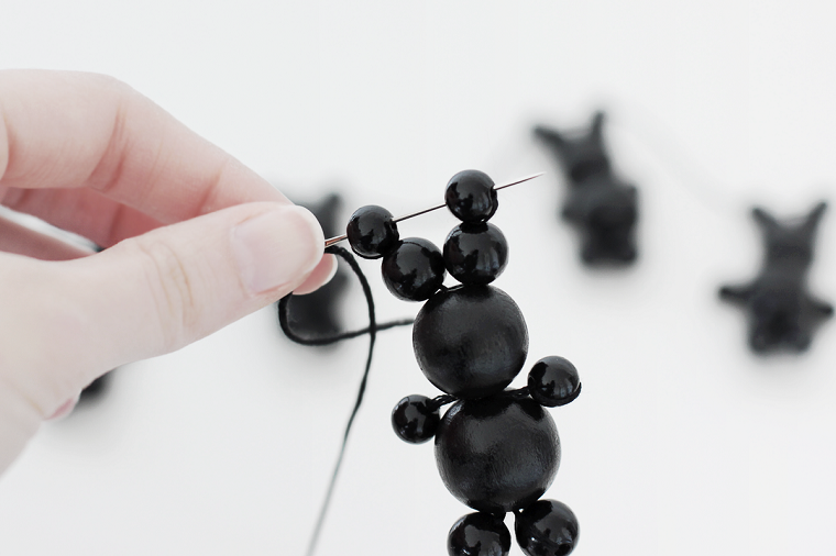 Coniglietto pasquale di palline in legno di colore nero, ago e filo di colore nero 