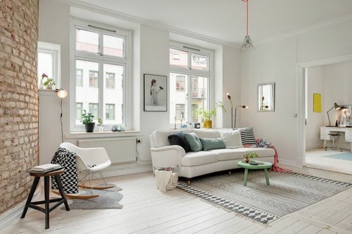 Soggiorno classico con un divano di colore bianco e parete con mattoni in vista 
