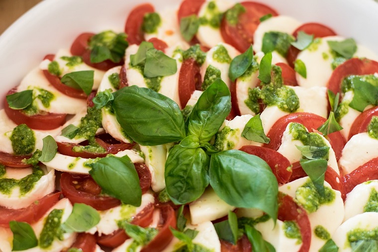 Ricette ipocaloriche e un'insalata caprese, pomodori a fette e mozzarella, decorazione con foglie di basilico 