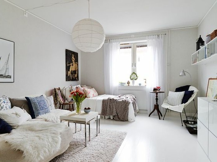 Camera da letto con un piccolo soggiorno, divano e tavolino basso, decorazioni con fiori e quadri 