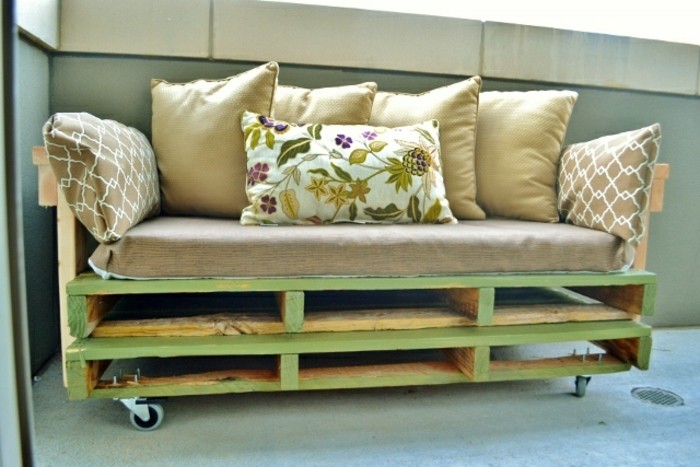 Arredamento con un divano in pallet, morbida cuscineria, bancale di legno dipinto di verde 