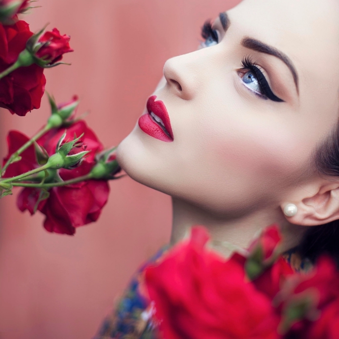 makeup rossetto rosso, occhi azzurri con eye liner nero, boccioli di rose rosse