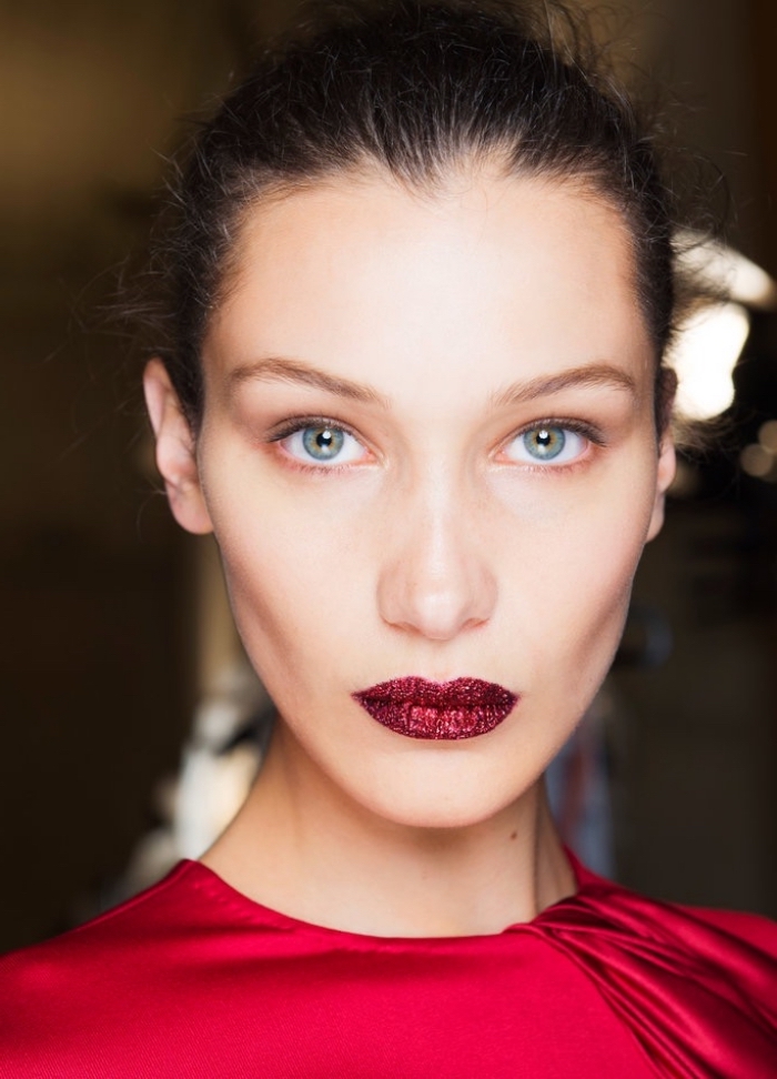 makeup nuove proposte con un rossetto rosso scuro, maglia rossa e occhi azzurri, capelli legati
