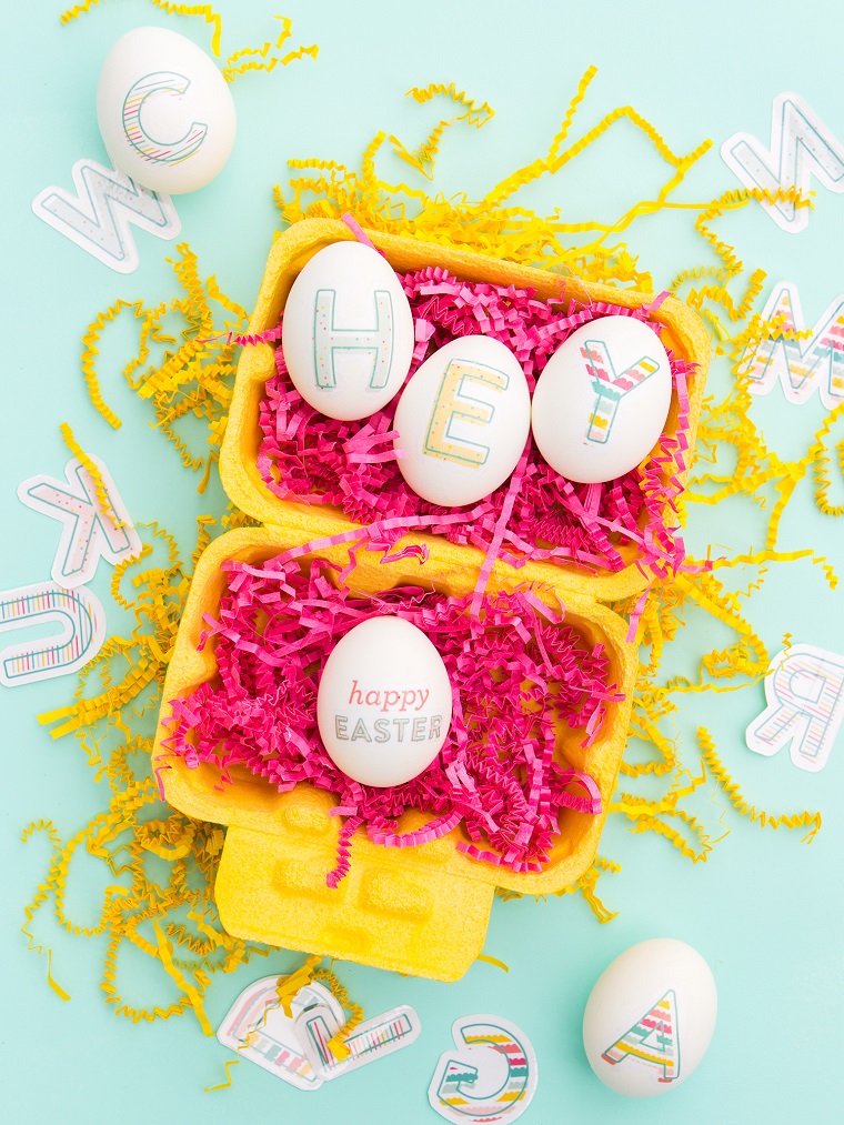 Uova di colore bianco decorate con lettere stickers, lavoretti pasquali 