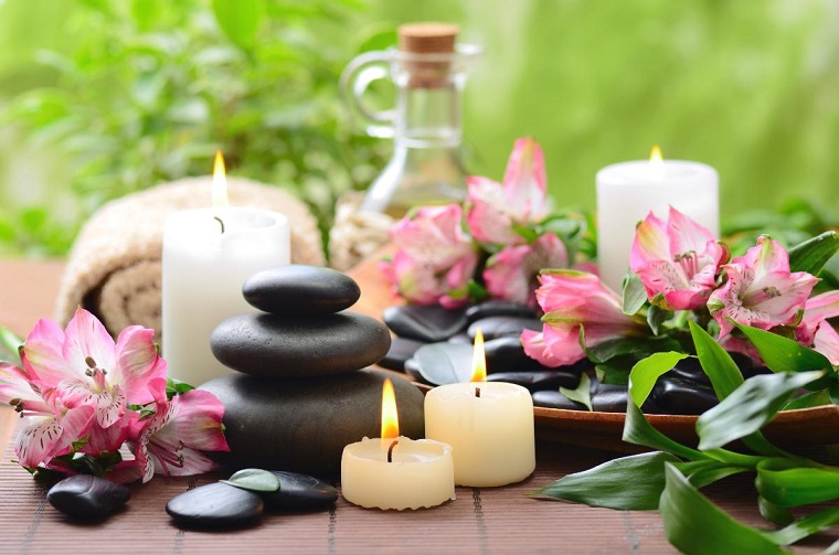 Cura con essenze vegetali, sassi zen in aromaterapia, candele e petali di fiori 