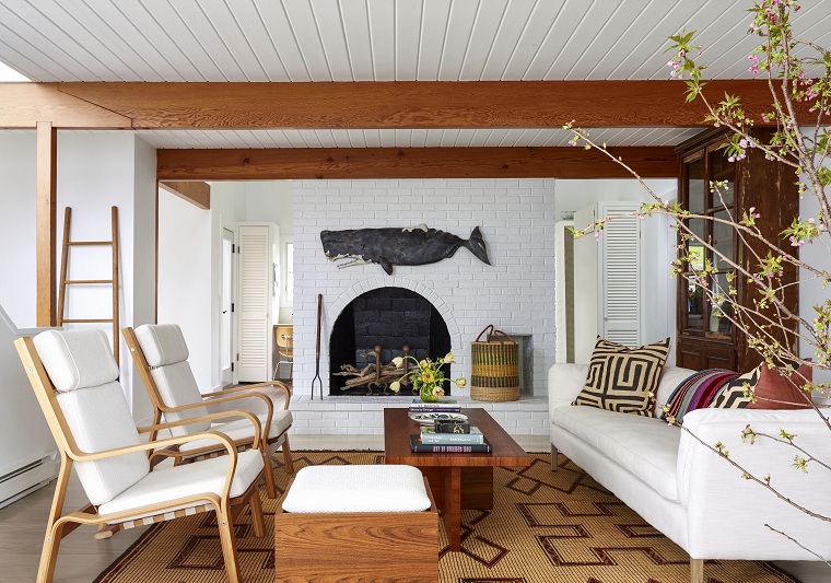 Interni case moderne, salotto con un set di mobili di colore bianco, camino a legna, parete con mattoni a vista bianchi 