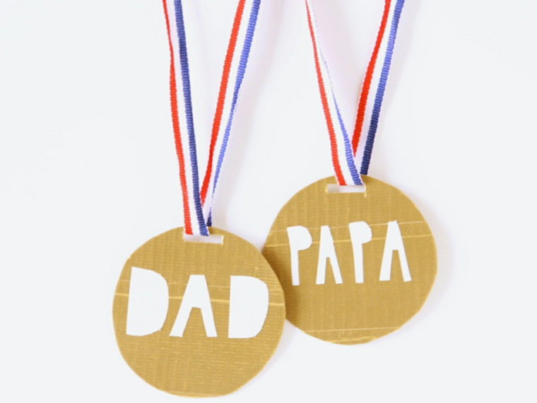 cartoncini con la scritta papà in bianco, delle medaglie come lavoretti festa del papà