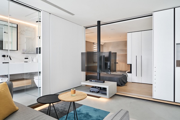 Arredamento moderno, un monolocale con bagno separato con porta a specchio, mobile tv colore bianco e lucido 