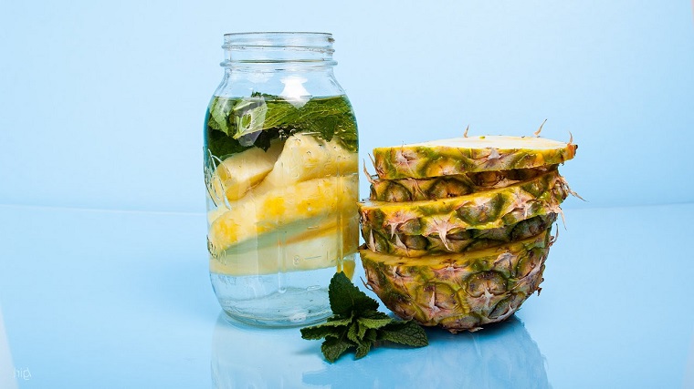 Barattolo di vetro con una bevanda sgonfia pancia a base di acqua e pezzettini di ananas 