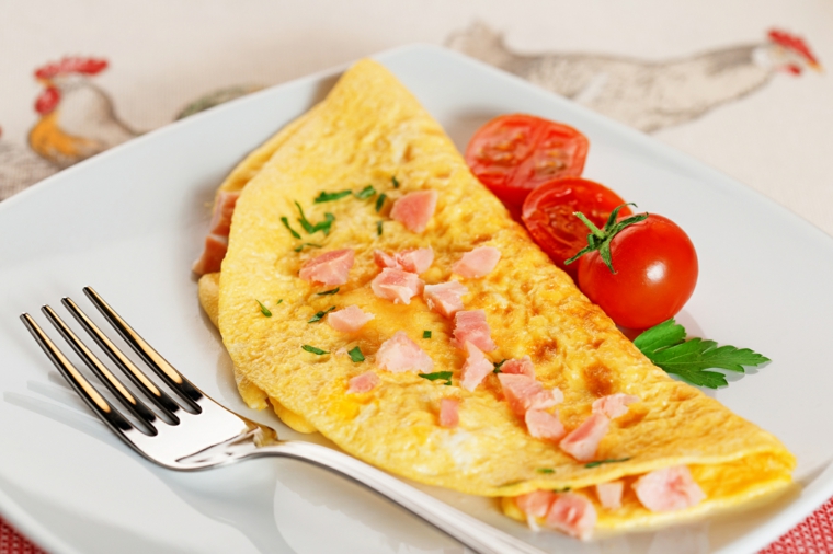 Omelette di uova con prosciutto a cubetti, contorno di pomodorini tagliati, secondi piatti semplici e gustosi 