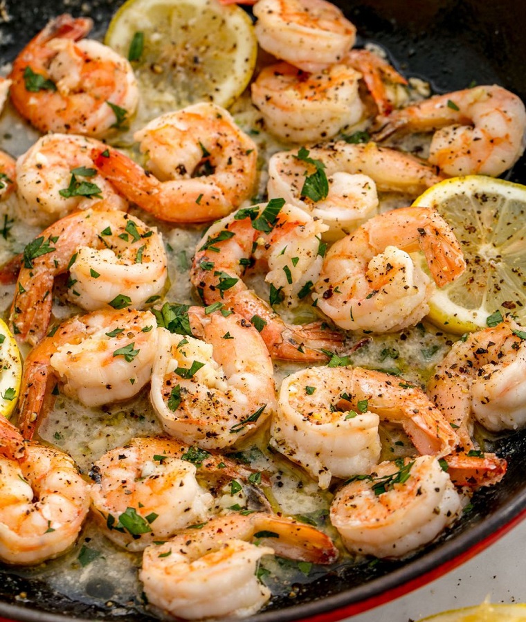 Scampi preparati in padella con salsa e pezzettini di limone, secondi piatti semplici e gustosi 