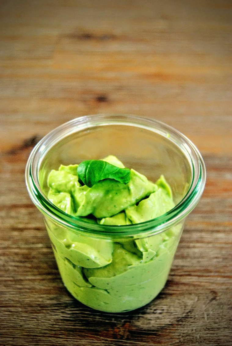 Come cucinare l'avocado, bicchiere di vetro con guacamole decorato con foglia di basilico 