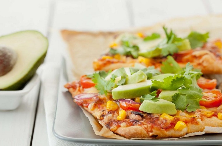 Come mangiare l'avocado, pizza messicana con pezzettini del frutto esotico e foglie di prezzemolo 
