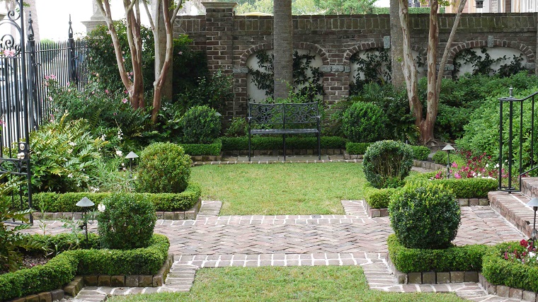 Piccoli giardini di villette, entrata di casa e siepi basse, recinzione con ringhiera di ferro battuto e muro in pietra 