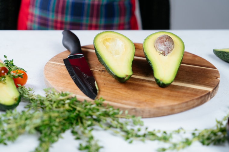Avocado tagliato a metà su un tagliere di legno, finger food con avocado fritto