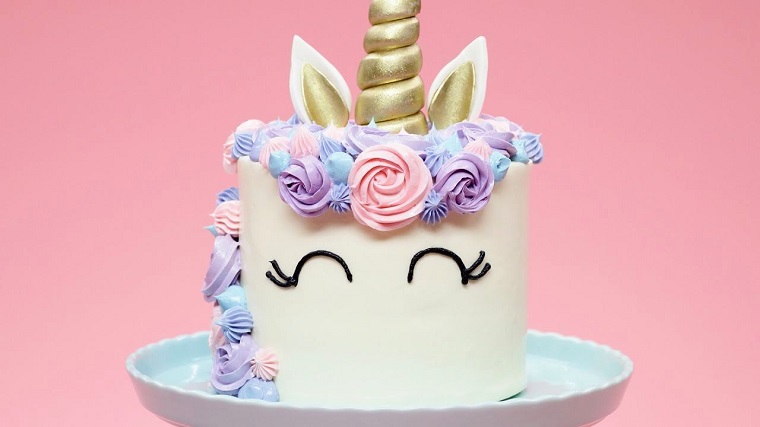 Piatto di porcellana con una torta a forma di unicorno, decorazione con panna colorata 