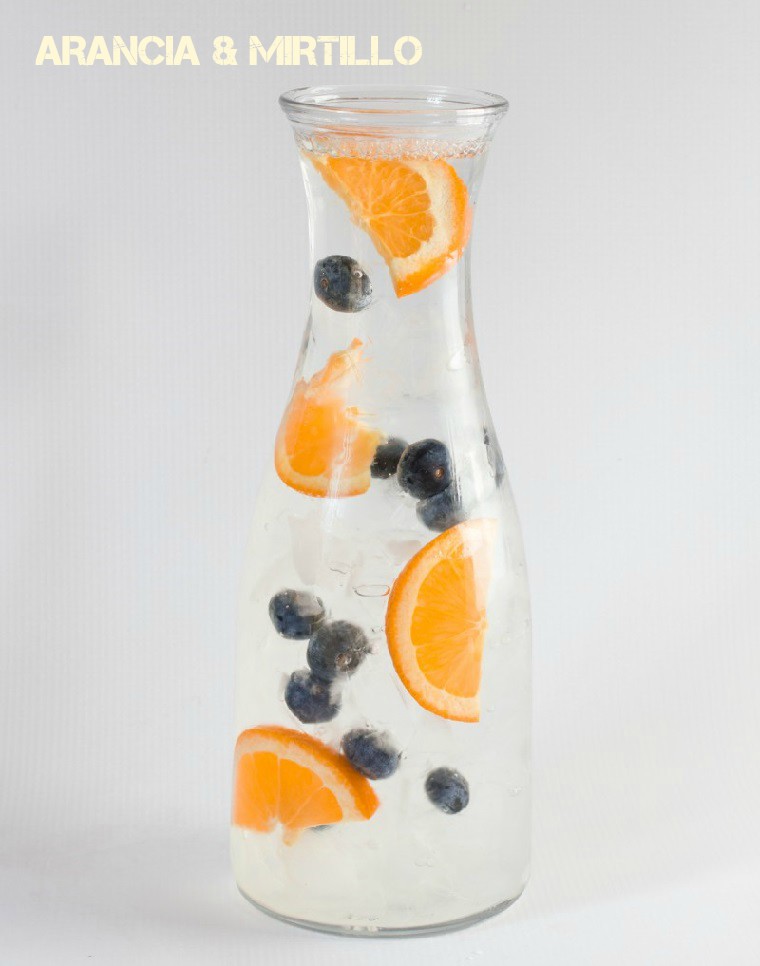 Ricette sgonfia pancia, bevanda a base di acqua, arancia e mirtillo, servita in una bottiglia di vetro 