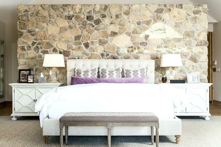 bellissima camera da letto con comodini vintage bianchi, parete rivestita in pietra