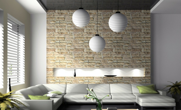 ampio e luminoso salotto con un divano in pelle bianco e cuscini verdi, lampadari bianchi e muri in pietra per interni