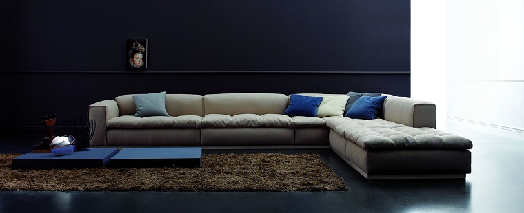 Come arredare un soggiorno con un divano angolare di colore grigio e tavolino molto basso blu 