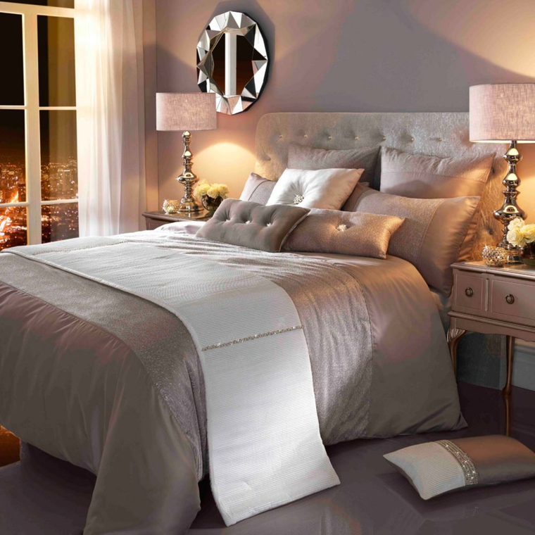 sofisticata camera da letto con copriletto. cuscini e pareti tortora chiaro, specchio tondo