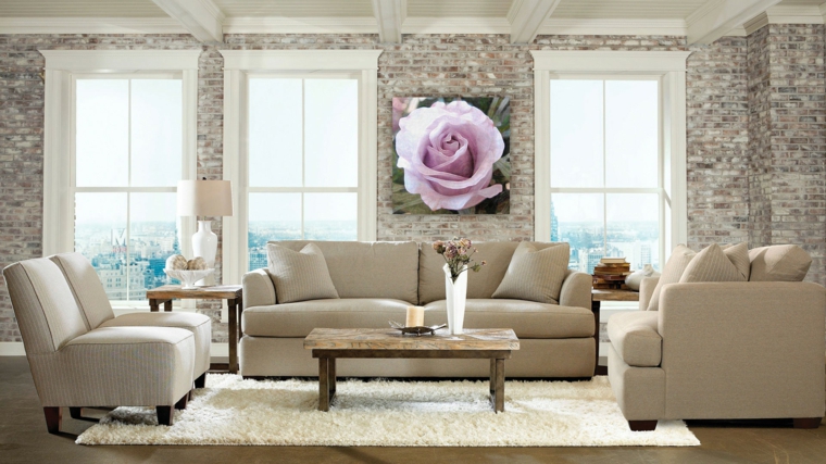 salotto arredato in stile elegante e moderno con divano e poltrone chiare, tappeto bianco e muri in pietra chiara